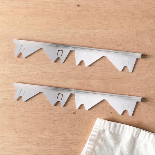 One pair (2 pieces) of adjustable silver steel stove gap covers lying flat on a wooden counter